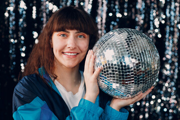Young sporty woman 80 and 90's style. 90s fashion positive girl at disco party with disco ball in...