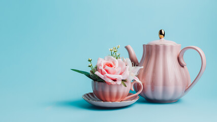 Creative layout with pink teapot and coffee cup filled with fresh flowers on pastel blue...