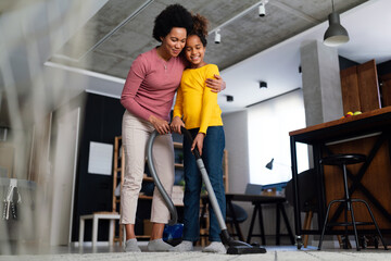 Single parent concept. Happy black mother have fun with daughter while do domestic chores together.