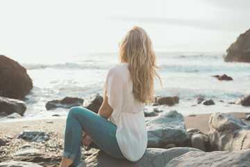 Fototapeta na wymiar Blonde Frau sitzt am Meer
