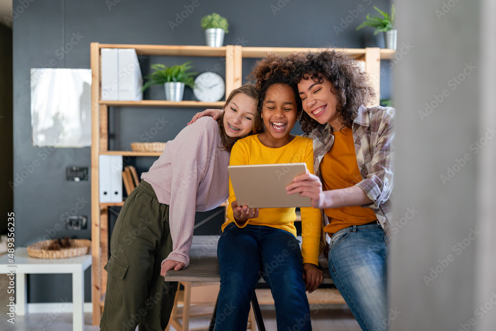 Wall mural Happy multiethnic teenagers holding technology gadgets using digital devices studying together.