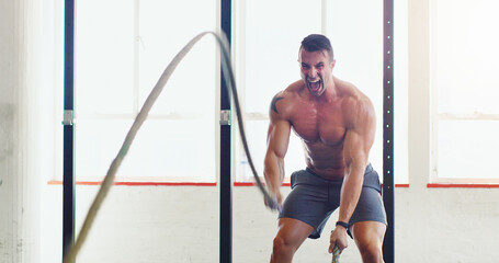 You dont need a machine to be one. Shot of a young man working out with battle ropes in a gym.