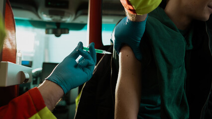 EMS Worker Giving a Shot to a Patient. Young Caucasian Male Getting a Vaccine Shot Done By a Medical Person.