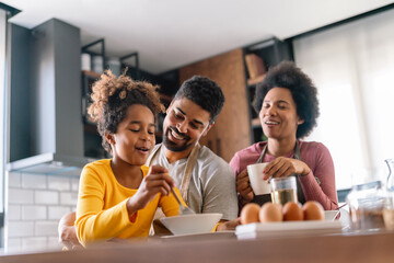 Overjoyed young african american family with daughter having fun in kitchen together