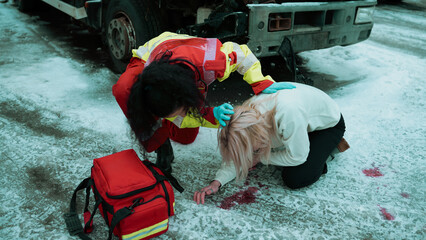Ethnic Female Paramedic Helping a Young Caucasian Teenager As She Lays on the Sidewalk Puking Blood After Surviving a Painful Car Crash, Face Covered in Blood Stains and Bruises. Ambulance at Work.
