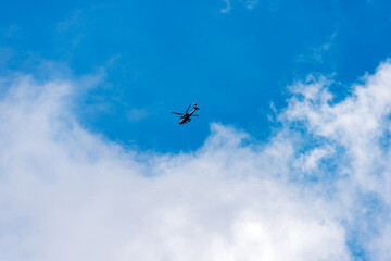 Italian military helicopter in motion against a clear blue sky with clouds, Italian Alps, Trentino-Alto Adige, Italy, Europe.