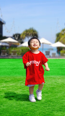 Happy Kid with big smiley face is running or jumping on the green field. Happy people concept.