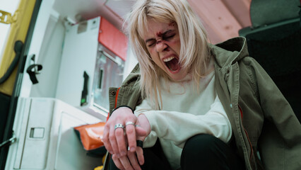 Young Caucasian Female Screaming in Agony, Face Covered  In Bruises and Blood, War Survivor Sitting...