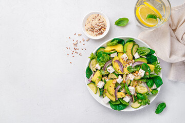 Vegetable salad with avocado, cucumber and feta on a gray background.