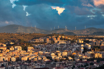 Wind turbines on the hills in Kusadasi Turkey with a city landscape in front.
