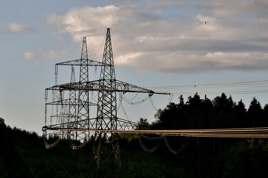 Eine 380 kv Leitung im mystischen Licht der Abendsonne f&uuml;hrt durch den Wald