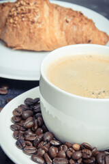 White cup of coffee and fresh croissant with chocolate