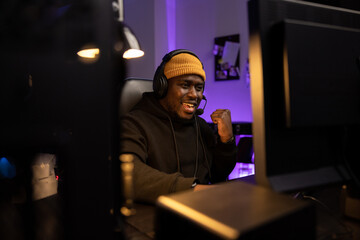 Portrait of delighted guy playing video games on computer in led-lit room man won a round in the game, passed the level, the joy of victory