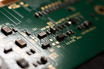 Macro photo of a green computer printed circuit board with selective focus on electronic components