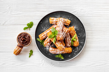 Fried churros with chocolate sauce and mint. Spanish sweets for breakfast