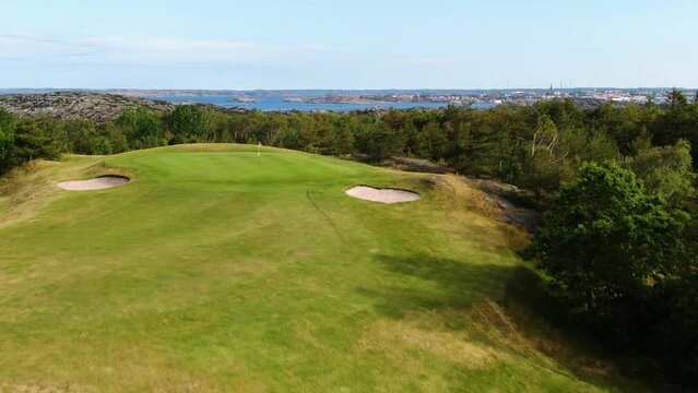 Golfer hits ball on green meadow of Golf club of Molndal near Gothenburg, Sweden. Aerial ascending