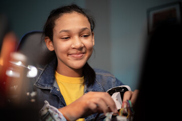 Smiling teenage girl staring at a laptop with instructions to repair a robot, the girl holds...