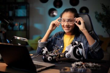 A teenager prepares to fix a toy. She puts on protective goggles for soldering. Girl fixes broken robot, tweaks remote control electronics