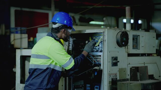 Caucasian maintenance engineer is using a torch to light a control cabinet to maintain normal operation in an industrial facility.

