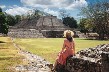 A young woman tourist sits against the backdrop of the Mayan ruins in the ancient city of Edzna.Edzna Campeche Mayan pyramids in Mexico. Concept travel.