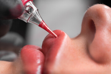 Close-up applying lip tattoo in beauty salon, permanent makeup of female lips, woman beauty
