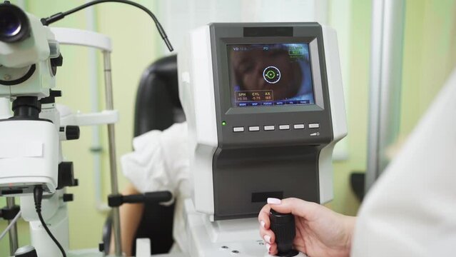 doctor examines child's eye on screen of autorefractometer. ophthalmic device.