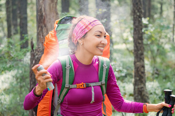 A female hiker sprays an aerosol to protect against blood-sucking insects and ticks, carriers of...