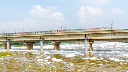 Fototapeta na wymiar View of a newly build metro rail bridge by Delhi Metro and polluted Yamuna river