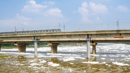Fototapeta na wymiar View of a newly build metro rail bridge by Delhi Metro and polluted Yamuna river