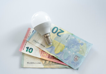 a light bulb on euro banknotes. Increase in the cost of electricity for residential customers and business users. Payment of electricity bills. Increasing the concept of electricity prices.