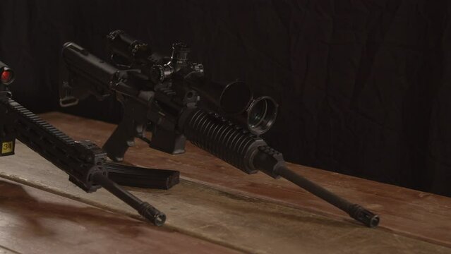 Dolly in of two AR 15 rifles standing on a wooden table