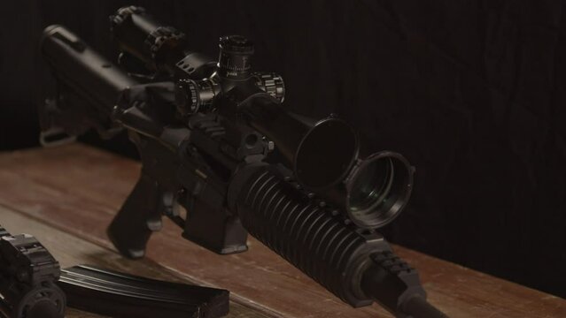 Close dolly of AR 15 rifle with scope standing on wooden table