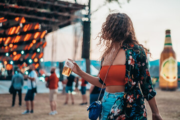 Fototapeta na wymiar Beautiful woman drinking beer and having fun on a festival with her friends