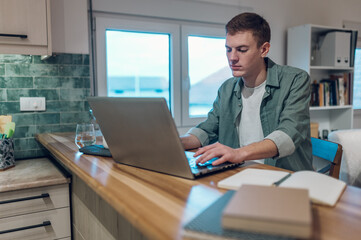Man using a laptop in the kitchen while working from home