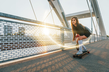 Young woman riding her longboard on the bridge - Powered by Adobe