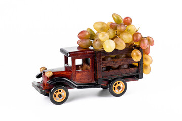 Grapes in toy wooden truck on white background.