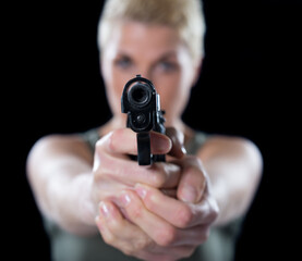 Young woman shooting with gun isolated on black background