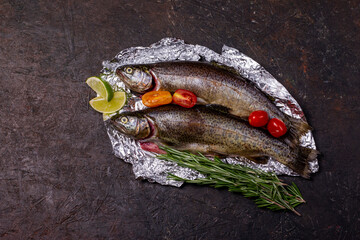 Raw fish, trout with on aluminum foil with ingredients for cooking. Fish, pepper, garlics,...