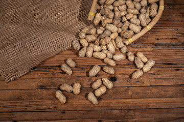 The container on the wood grain table is full of peanuts