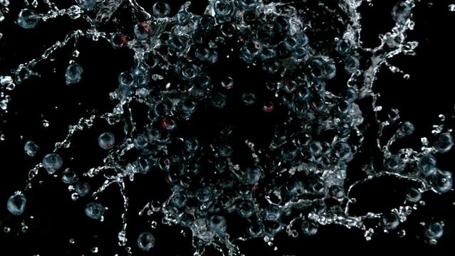 Super slow motion of rotating blueberries with splash water, black background. Filmed on high speed cinema camera, 1000 fps.