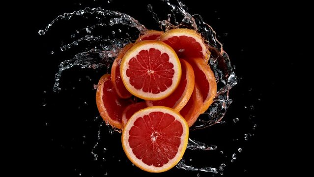 Super slow motion of rotating Grapefruit slices with splash water, black background. Filmed on high speed cinema camera, 1000 fps.