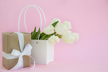 white tulips flowers in a paper bag on a pink background Place for text. Postcard. Holiday. Women's Day. Valentine's Day. mothers Day. online shopping concept