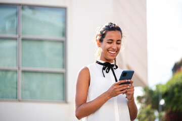 Fototapeta na wymiar young businesswoman using mobile phone outside and smiling