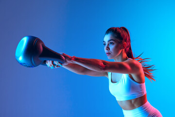 Strength training. Young sportive girl training with sports equipment isolated on gradient...