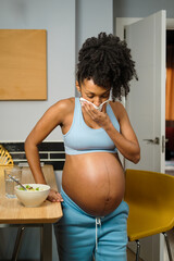 Young pregnant woman at home retching while eating dinner. Pregnancy sickness and nausea.