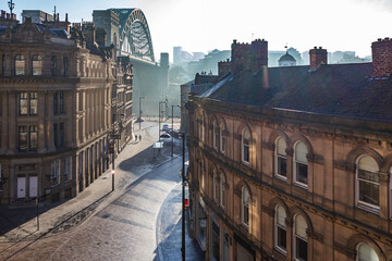 Newcastle Upon Tyne's famous Tyne Bridge and quayside in the historic Grainger Town part of the city, viewed from Queen Street at sunrise