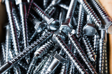 Galvanized large wood screws in a heap close-up.