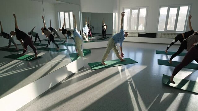 Yoga teacher man giving lesson to female group in yoga studio