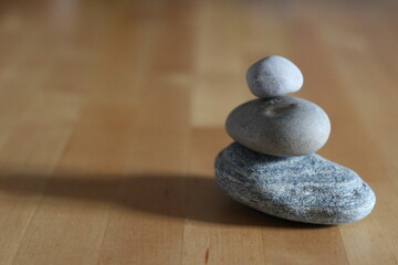 Fototapeta na wymiar 木目のある机の上の積み重なる３つの石