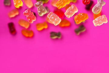 Multicolored flying gummy bears on a pink background, flat lay